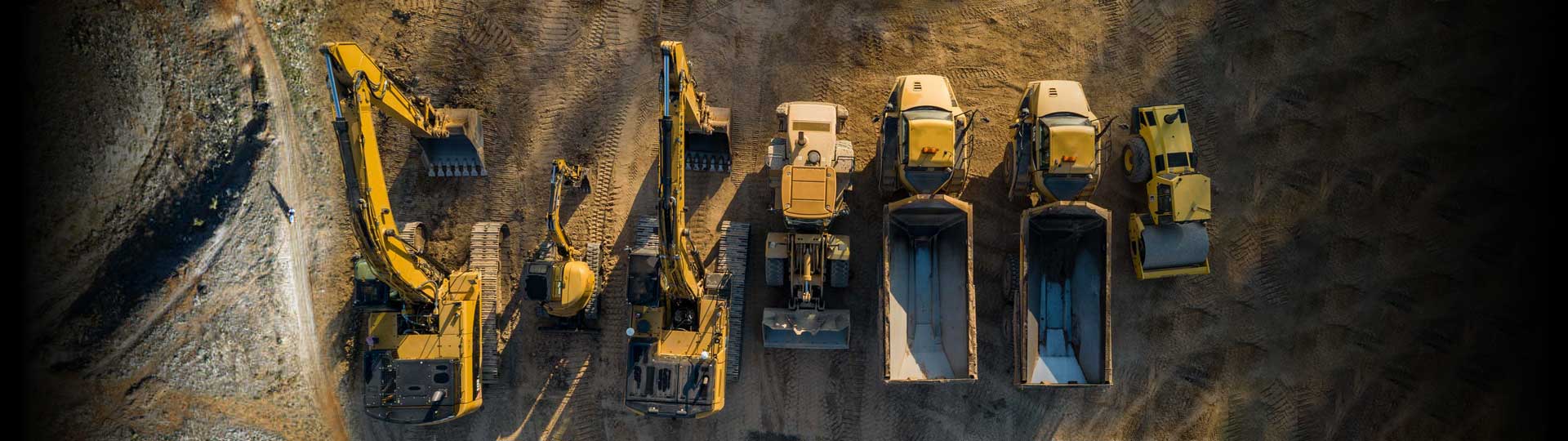 Three excavators, a backhoe, two trucks and a paving flattening machine