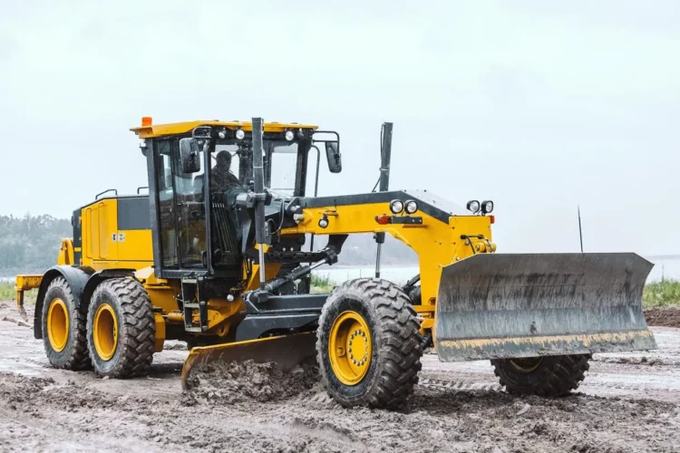 A yellow bulldozer is driving on a dirt road