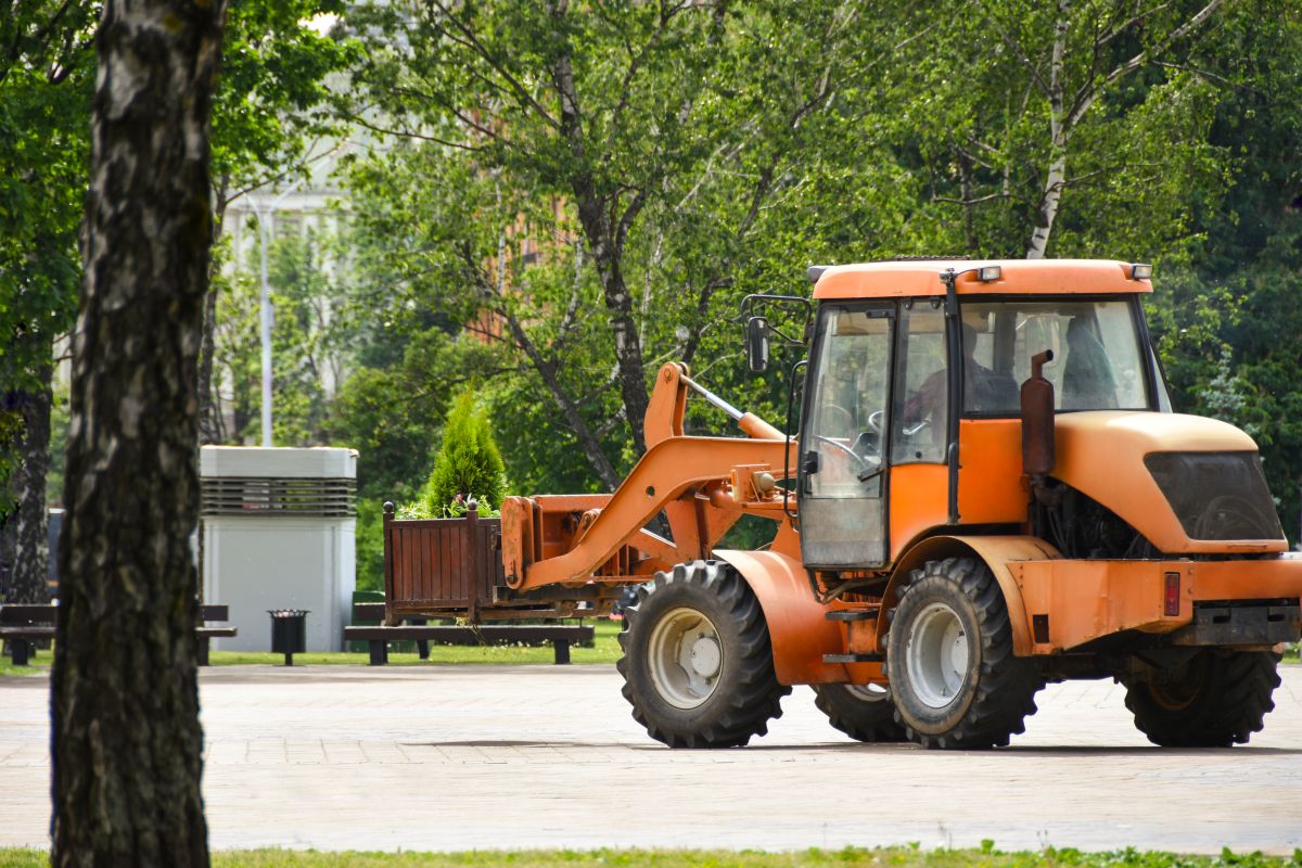 Compact wheel loader operating in an urban park area in Dublin, CA, performing light construction or landscaping work.