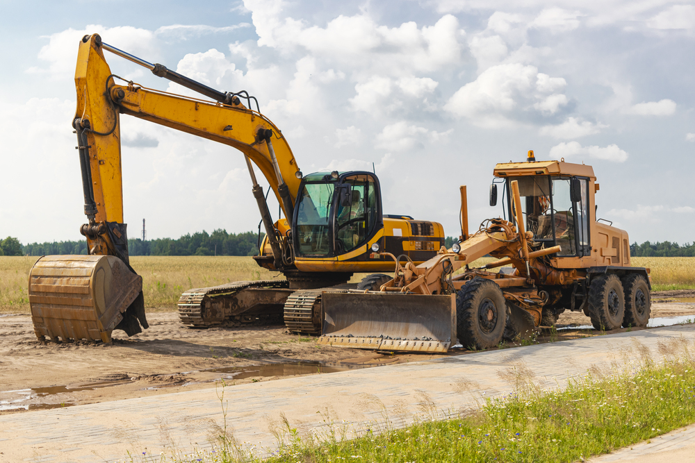 Excavator and grader preparing ground at a construction project in Flushing, NY