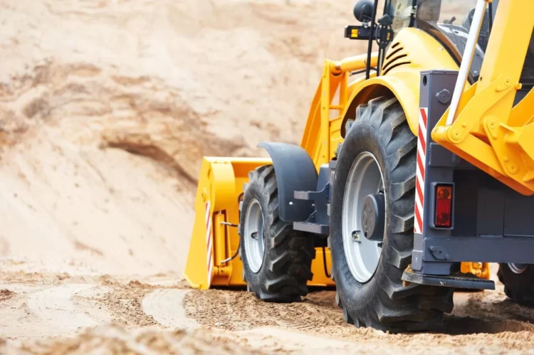 A yellow bulldozer is driving down a dirt road.
