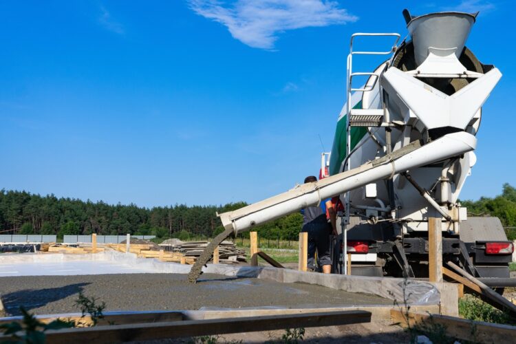 Worker pouring concrete at a construction site.
